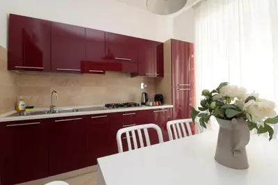 a kitchen with red cabinets and a vase of flowers on a table at Cardinal Vatican Inn in Rome