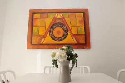 a vase with flowers on a table with a painting at Cardinal Vatican Inn in Rome