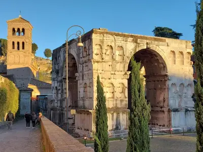 an old building with an arch and a church at Palazzo Velabro, a Member of Design Hotels in Rome