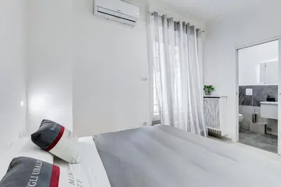 a white bedroom with a bed and a large window at Vatican 96 Degli Ubaldi Charming Suite with terrace in Rome