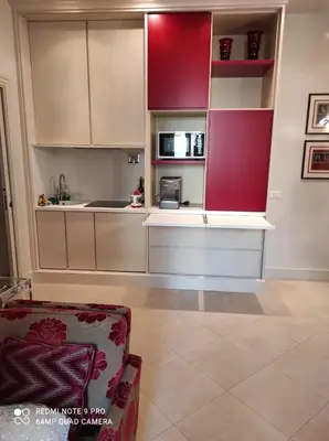 a kitchen with red and white cabinets and a couch at Popolo square deluxe flat in Rome