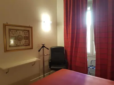 a bedroom with a chair and a red curtain at Popolo square deluxe flat in Rome