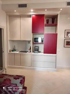 a kitchen with white cabinets and a red wall at Popolo square deluxe flat in Rome