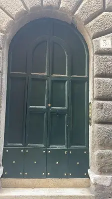 a large green door in a stone building at A.D. Navona Apartment in Rome