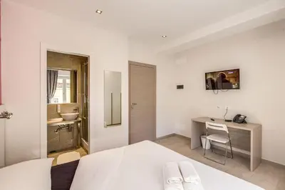 a white bedroom with a bed and a desk at Aurelia Vatican Suites in Rome