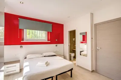 two beds in a room with a red wall at Aurelia Vatican Suites in Rome