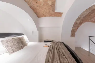 a bedroom with a white bed and a brick wall at iFlat Trastevere Unique Loft in Rome