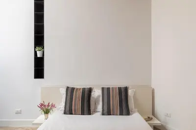 a bedroom with a white bed with two striped pillows at iFlat Trastevere Unique Loft in Rome