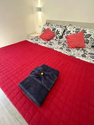 a bed with a red comforter and red pillows on it at Lotto 30 Metro Garbatella in Rome