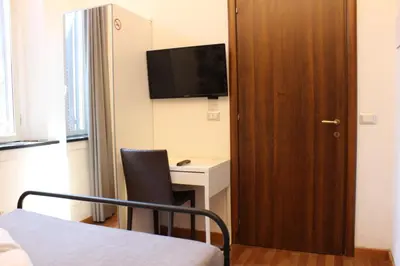 a room with a bed and a desk with a television at Rooms Piramide in Rome