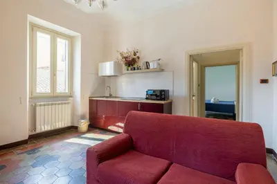 a living room with a red couch and a kitchen at CHARMING APARTMENT AT SPANISH STEPS, no elevator in Rome