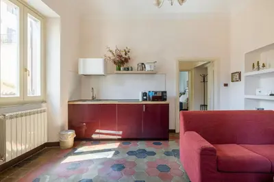 a living room with a red couch and a kitchen at CHARMING APARTMENT AT SPANISH STEPS, no elevator in Rome