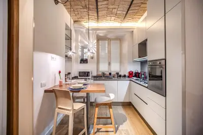a kitchen with white cabinets and a wooden table and chairs at PgrHome Borgo Vittorio in Rome