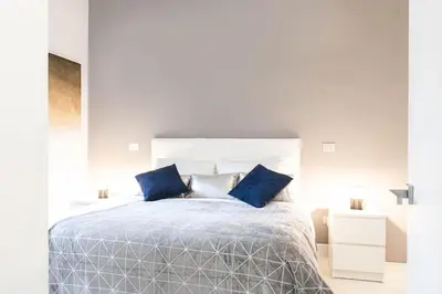 a white bedroom with a large bed with blue pillows at Manara 57 Dream Apartment Trastevere in Rome