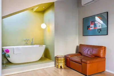 a bathroom with a tub and a leather couch at Rome As You Feel - Luxury Terrace in Navona in Rome