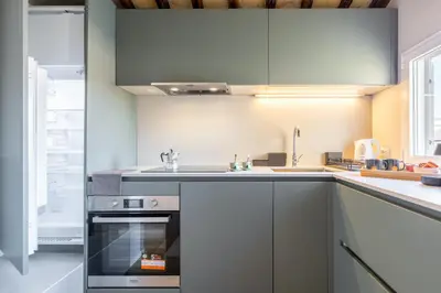 a kitchen with white cabinets and a sink and an oven at Rome As You Feel - Luxury Terrace in Navona in Rome