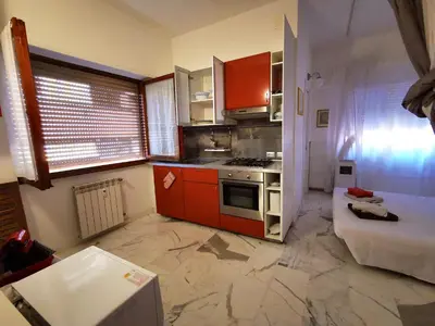 a small kitchen with orange cabinets and a stove at Rouge Studio - 10 min from Vatican in Rome