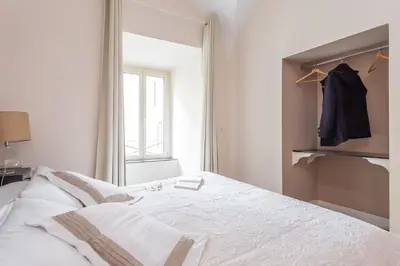 a white bedroom with a bed and a window at Daplace - Lucia Apartment in Rome