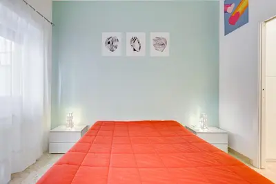 a white room with a bed with an orange blanket at JMartins Vatican suites in Rome