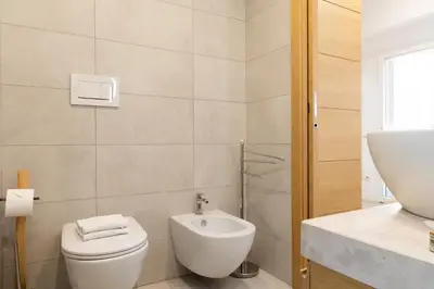 a white bathroom with a toilet and a sink at Casa Camilla in Rome