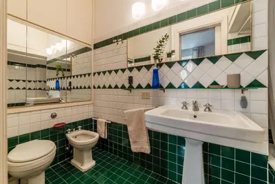 a green and white bathroom with a toilet and a sink at Colosseum - Charme Holidays in Rome