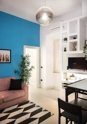 a living room with a pink couch and a blue wall at Domus Colosseum by JFM - Cozy apartment nearby Colosseum in Rome