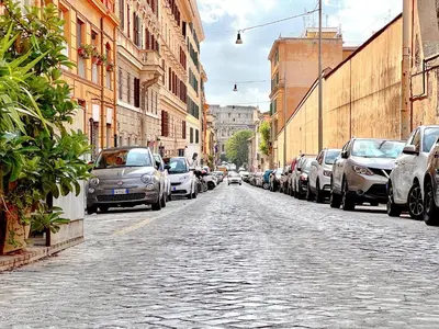 a cobblestone street with parked cars in a city at Domus Colosseum by JFM - Cozy apartment nearby Colosseum in Rome