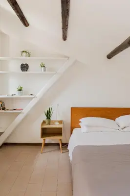 a white room with a bed and a table and shelves at La mansarda del Papa - ZENO 05 in Rome