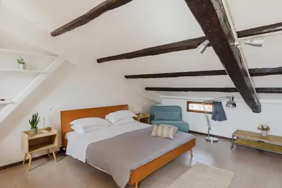 a bedroom with a bed and a blue chair at La mansarda del Papa - ZENO 05 in Rome