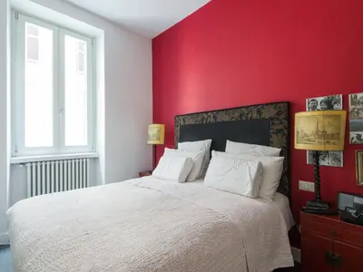a bedroom with a white bed with a red wall at Apartment San Salvatore by Interhome in Rome