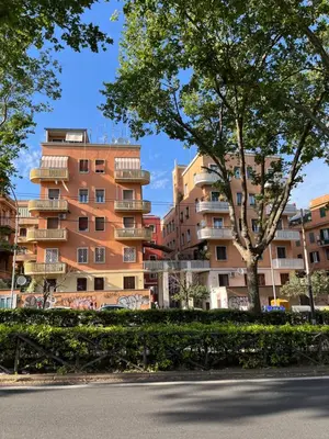 a building with a tree in front of a street at Red house in Monteverde - Cale 02 in Rome