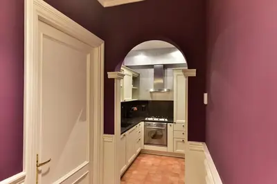a kitchen with purple walls and an arched doorway at Residenza Clodio Spanish Steps in Rome