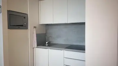 a kitchen with white cabinets and a sink and a microwave at GreenSpace Romantic Studio - Piazza del Popolo in Rome