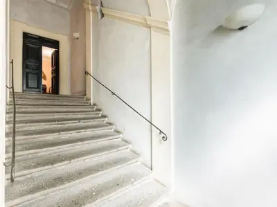 a staircase in a white building with a black door at Apartment in a 1400s building in Via dei Coronari Piazza Navona in Rome
