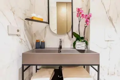 a bathroom sink with a mirror and a vase of flowers at Trastevere Boutique with Gym and Steam Shower in Rome