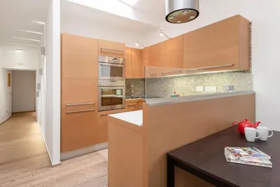 a kitchen with wooden cabinets and a counter top at Modern Colosseum Flat in Rome