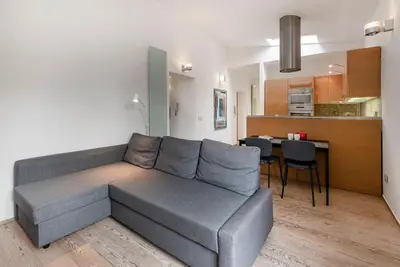 a living room with a gray couch and a kitchen at Modern Colosseum Flat in Rome