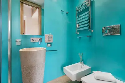 a bathroom with blue walls and a sink and a mirror at Modern Colosseum Flat in Rome