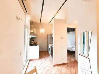 a kitchen with white appliances and a room with a bed at Cozy Apartment in Pigneto up to 4 in Rome