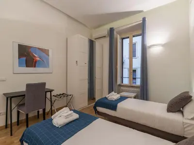 a room with two beds and a desk and a window at The Best Rent - Elegant flat near Colosseum in Rome