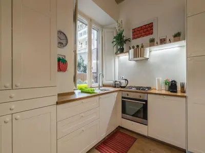 a kitchen with white cabinets and a red rug at The Best Rent - Elegant flat near Colosseum in Rome