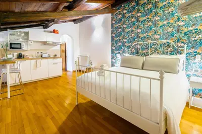 a bedroom with a white bed and a kitchen at Magikrooms Muse in Rome