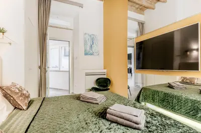 a bedroom with two beds and a flat screen tv at TH Trastevere Luxury-S.Cosimato 2bd-2bt in Rome