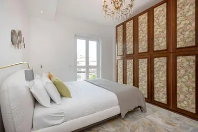 a white bedroom with a large bed and a chandelier at Vatican Dome View Apartment in Rome