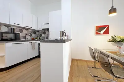 a kitchen with white cabinets and a counter with chairs at 4BNB - Cozy Albornoz Flat in Rome