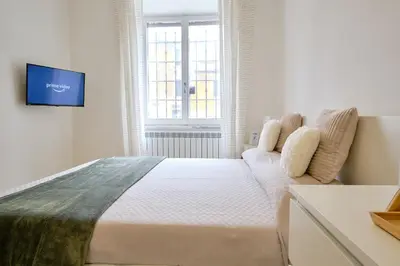 a white bedroom with a bed and a tv on a wall at Remuria Domus in Rome