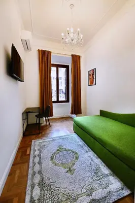 a green couch in a living room with a chandelier at St Peter Regal Apartment in Rome
