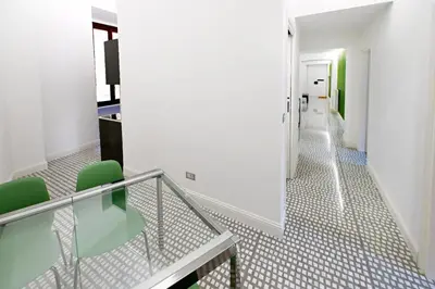 a hallway with a glass table and green chairs at St Peter Regal Apartment in Rome