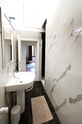 a white bathroom with a sink and a mirror at St Peter Regal Apartment in Rome