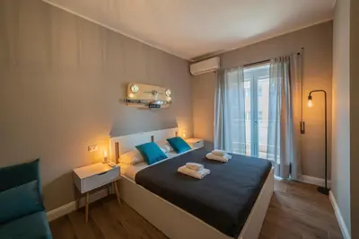 a bedroom with a bed with blue pillows and a window at Vintage Cipro Apartment in Rome